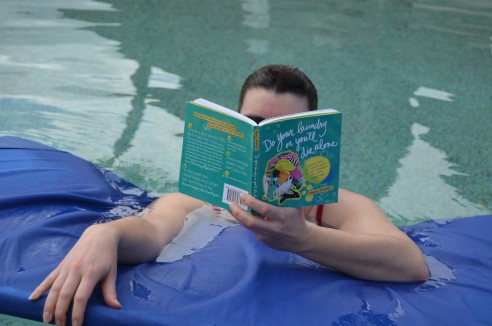 boy reading laundry or die book in pool